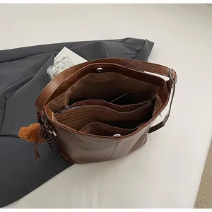 Vue intérieure montrant la doublure rayée et le compartiment zippé du sac en cuir marron