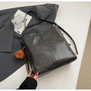Détail du sac seau gris foncé avec coutures verticales et un pendentif ours mignon