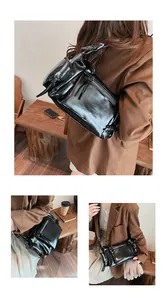 Gros plan sur la surface en similicuir noir brillant et les zips de ce sac bandoulière