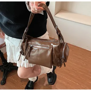 Détail du sac à bandoulière en cuir verni marron foncé avec fermetures éclair argentées
