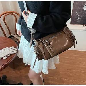 Détails d'un sac bandoulière vintage en cuir marron avec fermetures éclair et franges