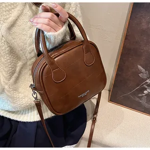 Detail of vintage dark brown crocodile pattern leather handbag with twin handles and strap