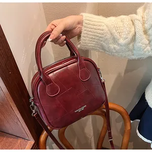 Detailed texture of burgundy leather patchwork on vintage crossbody bag with dual zippers