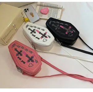 Close-up of coffin-shaped cross print crossbody bags in black, white, and pink leather