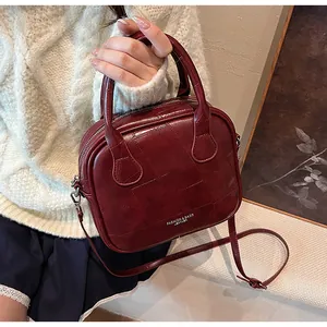 Close-up of wine red vintage pillow bag with stitching details and leather logo