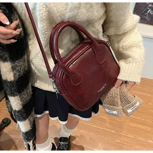 Close-up of a retro deep red patchwork handbag with adjustable shoulder strap and leather texture