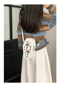Detailed view of a white coffin-shaped crossbody bag with a gothic cross on a model