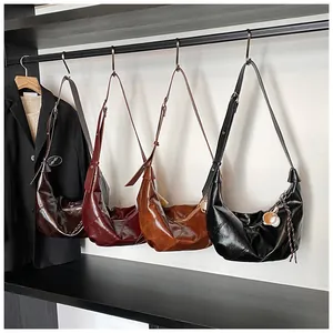 Varios bolsos hobo de cuero PU brillante colgados en un armario de moda elegante