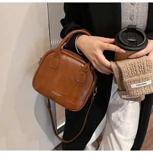 Close-up of brown vintage leather crossbody bag featuring checkered embossing and top handles