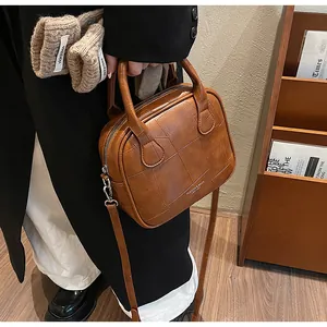 Detail of caramel leather handbag featuring geometric stitching and silver buckles