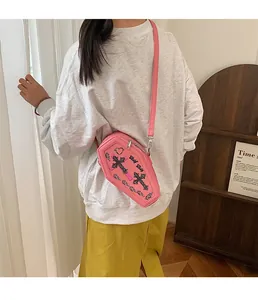 Cross print pink coffin-shaped crossbody bag shown on model for size and style reference