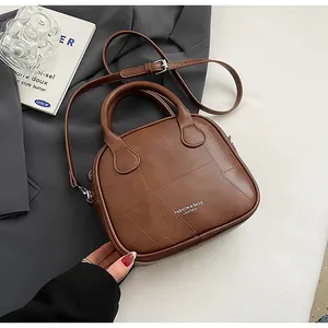 Detail of coffee brown PU leather bag with vintage patchwork stitching and top handles