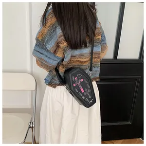 Gothic black coffin-shaped crossbody bag with pink cross embroidery worn by a model