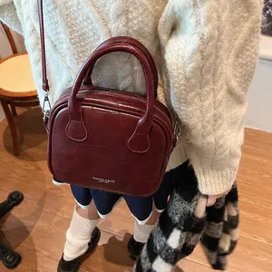 Vintage burgundy leather crossbody pillow bag with top handles shown on model outfit