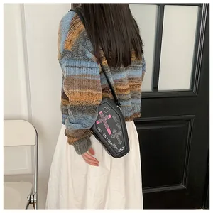 Detail showing the coffin-shaped crossbody bag with pink embroidered cross and PU texture