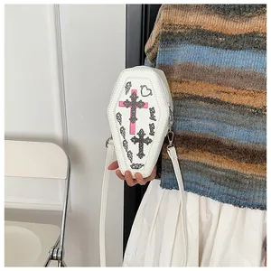 Gothic coffin-shaped crossbody bag with cross prints and white strap held by model