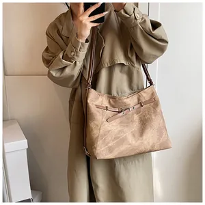 Detail of vintage brown tote bag showing textured leather, metal buckle and eyelet belt