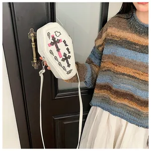 Detail of white coffin-shaped crossbody bag with pink cross print and leather strap