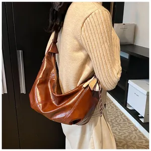 Detalle del bolso hobo de cuero encerado brillante marrón caramelo con un colgante
