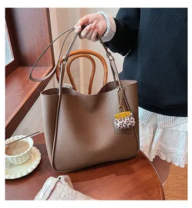 Close-up of brown litchi pattern tote bag with a leopard print mini charm detail