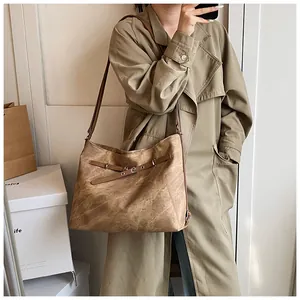 Detail of vintage brown tote bag texture and adjustable strap on a classic trench coat