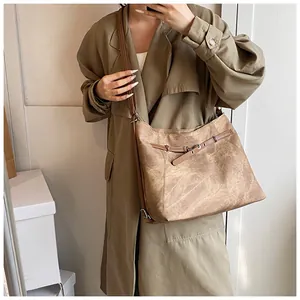 Detail of vintage brown tote bag with matte texture and metallic buckle on model