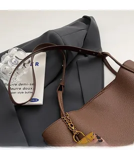 Detail view of brown pebbled leather tote bag with gold chain and leopard silk scarf