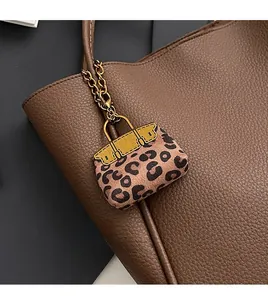 Detail of a leopard print mini bag charm with gold chain on a large tote bag