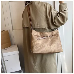 Close-up of vintage brown tote bag with matte texture and buckle detail on a model