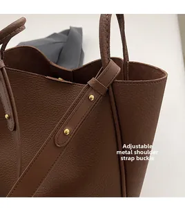 Detail of adjustable strap with gold-tone hardware on dark brown leather tote bag