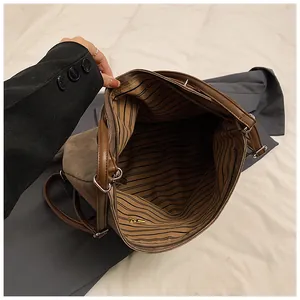 Detail view of large brown vintage tote bag showing striped lining and metal ring connectors