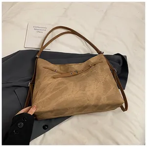 Close-up of vintage brown suede tote bag with metallic eyelet detailing and leather straps