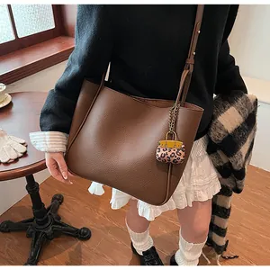 Detailed texture of brown pebble leather tote bag with a leopard print mini pouch charm