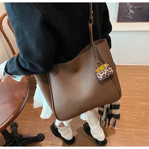 Close-up of brown lychee texture tote bag featuring a stylish leopard print charm