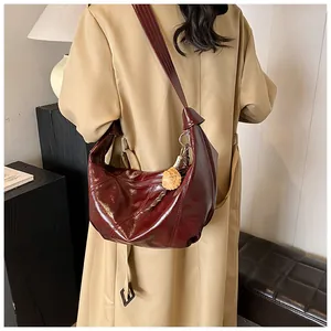Detalle del bolso de cuero brillante burdeos llevado con una gabardina caqui