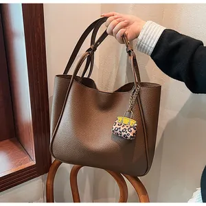 Detailed texture of dark brown pebbled leather tote with leopard print mini bag charm