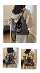 Detail view of large dark brown retro tote bag with golden buckles and baseball pendant