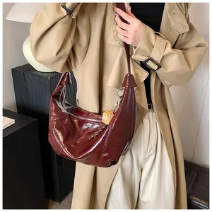 Detalle del bolso hobo de media luna granate con costuras y colgante de oso