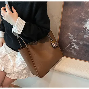 Brown lychee leather tote bag featuring a leopard charm and metal chain detail