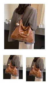 Detail of a large brown hobo bag with leather straps and a cute baseball charm