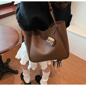 Detail of dark brown pebble leather tote bag with a leopard print mini pouch charm