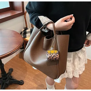 Detailed shot of brown textured leather tote bag with leopard print mini charm pendant