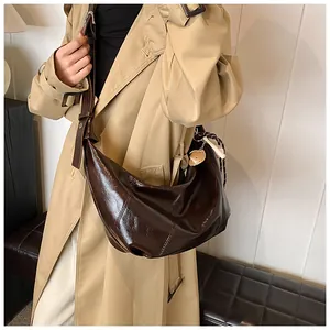 Detalle del bolso hobo de cuero marrón oscuro con correa ajustable y colgante fresa