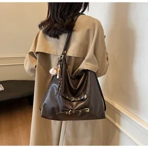 Detailed shot of dark brown tote bag with metal buckles and a mini baseball charm