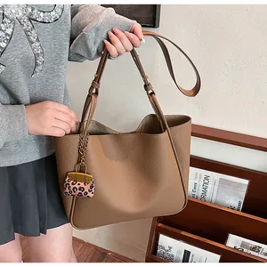 Close-up of brown pebbled leather tote with a stylish leopard print mini bag charm