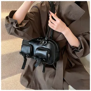 Detail of a black leather underarm bag featuring side zip pockets and silk bow accents