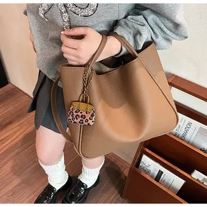 Detail of brown leather tote bag with leopard print mini charm on golden chain