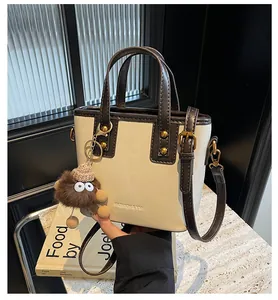 Détail d'un sac à main bicolore en similicuir avec garnitures dorées et breloque