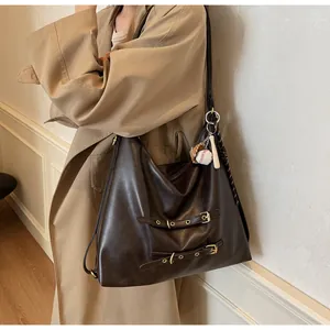 Detail view of large dark brown retro tote bag with buckle straps and a baseball keychain