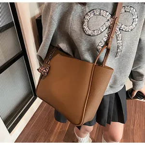 Close-up of brown pebbled leather tote bag with a pink leopard heart charm and strap